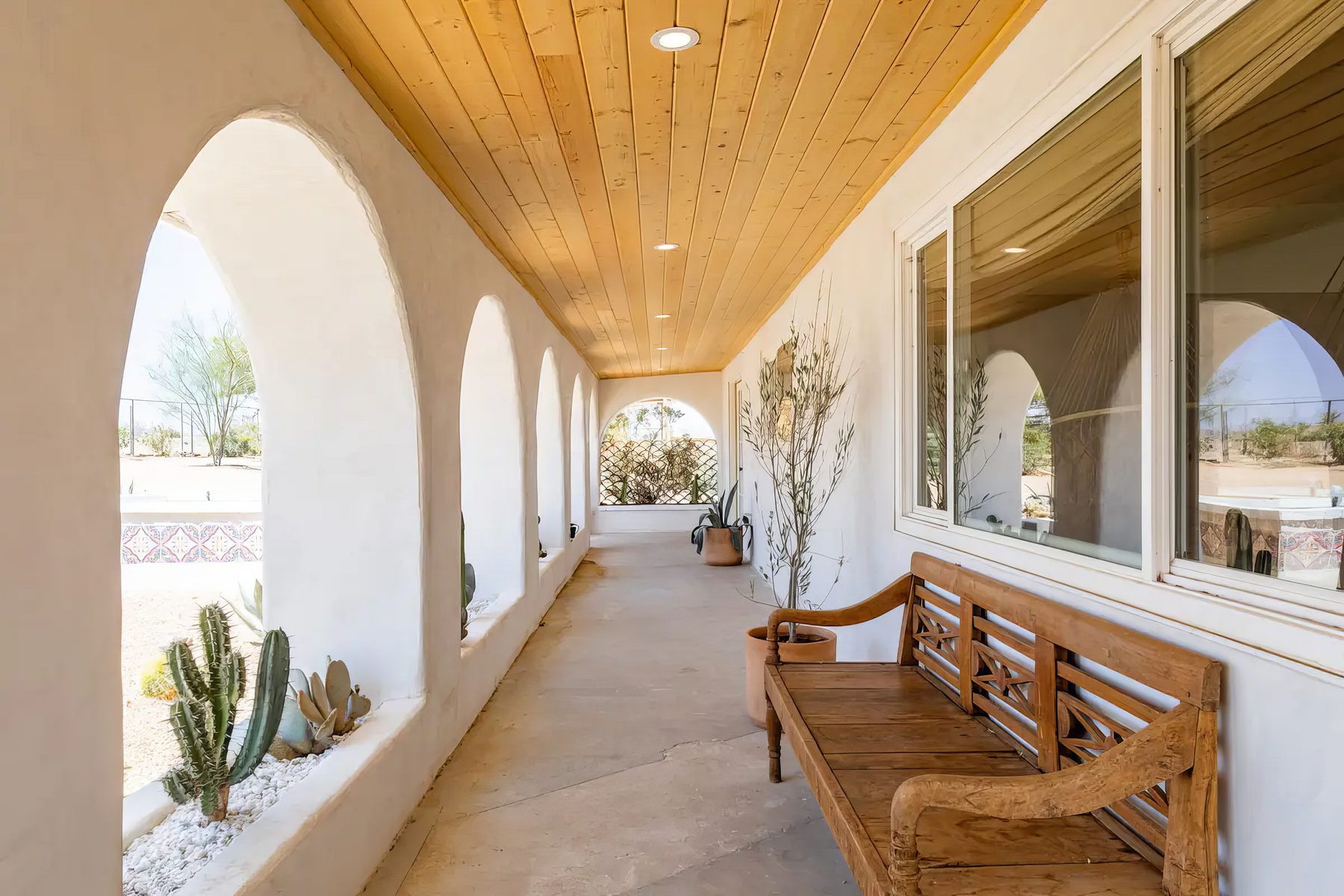 The arcade at Seven Arches — hand-shaped white plaster arches opening onto cactus beds under a pine ceiling